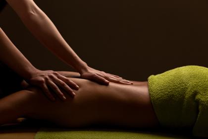 Therapist massaging a client’s back with warm herbal poultices